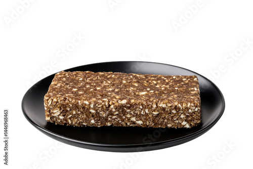 Rectangular cereal bar on plate. Dark background highlighting texture and form of food