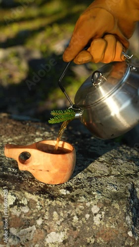 Wallpaper Mural Hot tea is being poured from a camping kettle into a mug. A traditional kuksa cup and hot tea. Hot tea in a coniferous forest. Torontodigital.ca