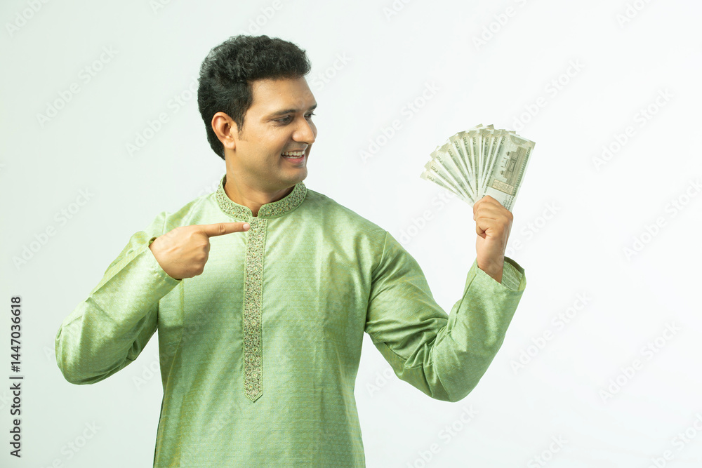 Indian happy traditional young happy man pointing finger to indian rupees note while wearing ethnic mint kurta pajama on white background Indian happy traditional young happy man pointing finger to indian rupees note while wearing ethnic mint kurta pajama on white background