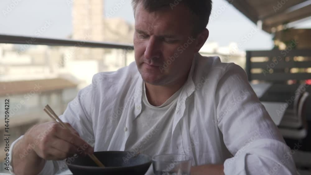 A man skillfully uses chopsticks to enjoy a delicious meal A man skillfully uses chopsticks to enjoy a delicious meal