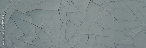 Obraz na płótnie Peeling paint on the wall. Panorama of a concrete wall with old cracked flaking paint. Weathered rough painted surface with patterns of cracks and peeling. Panoramic texture for background and design. w salonie
