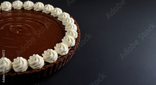 Elegant Chocolate Tart with Whipped Cream Border on Dark Background with copy space