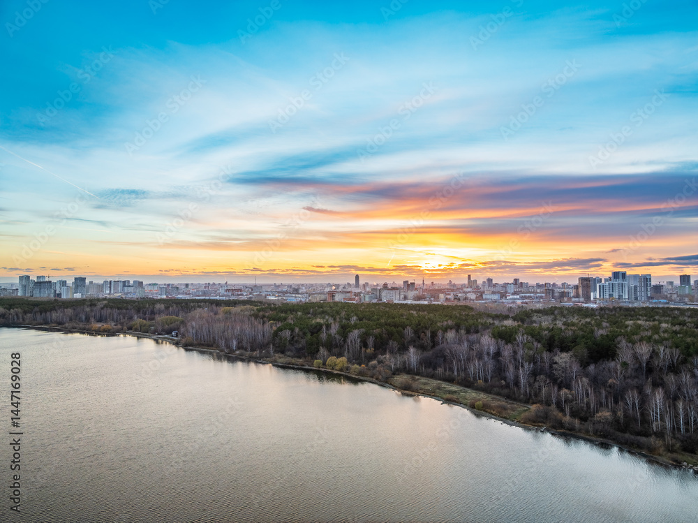 Fototapeta premium Colorful autumn forest with trees on the shore of a blue lake - top aerial view.