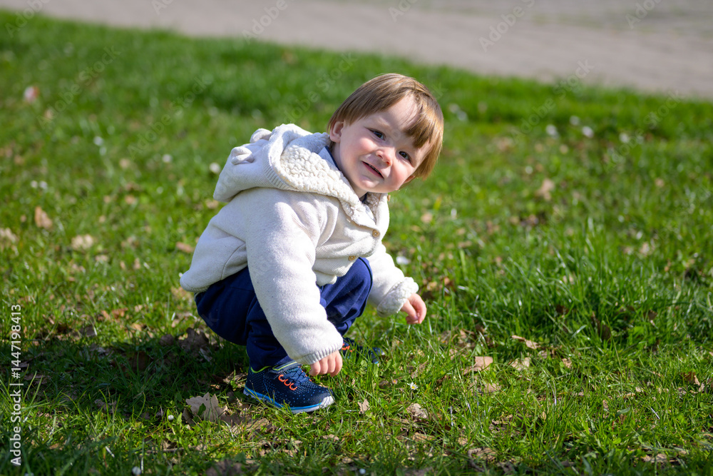 Smiling Toddler Squats In Grass Smiling Toddler Squats In Grass