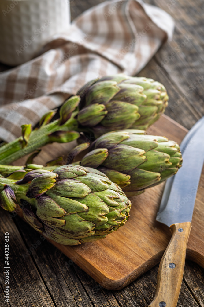 Fototapeta premium Ripe artichokes plant on cutting board.