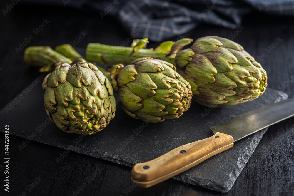 Fototapeta premium Ripe artichokes plant on cutting board.