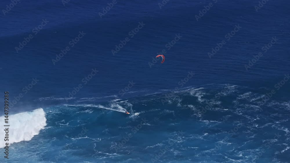 Kiteboarder riding big wave in clear tropical ocean waters, top aerial view Kiteboarder riding big wave in clear tropical ocean waters, top aerial view