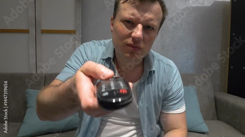 A man nervously switches channels with a TV remote control, throw away the TV remote control. Angry man. Slow motion