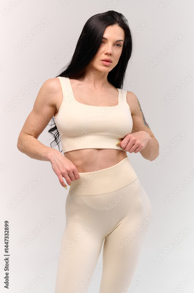 Fototapeta premium Smiling sporty woman in white underwear posing on studio background with copy space. Female beauty, sport, spa concept