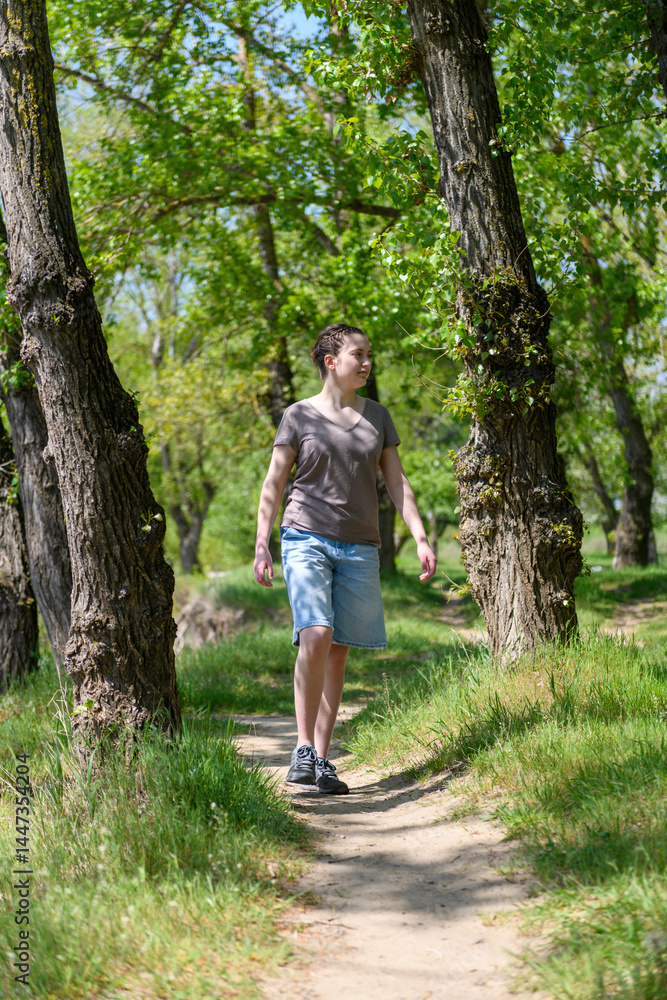 Teen girl a girl walks along a forest path, beautiful spring nature, green leaves, landscape Teen girl a girl walks along a forest path, beautiful spring nature, green leaves, landscape
