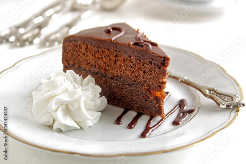 A piece of chocolate Sacher torte on a white plate