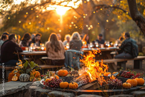 Fototapeta Naklejka Na Ścianę i Meble -  A delightful gathering of friends and family cozily gathered around a warm fire pit, celebrating beauty of autumn with a festive Thanksgiving party adorned with charming fall decor    