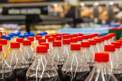  Rows of soda bottles with red caps on grocery store shelf, retail beverage display and consumer choice concept