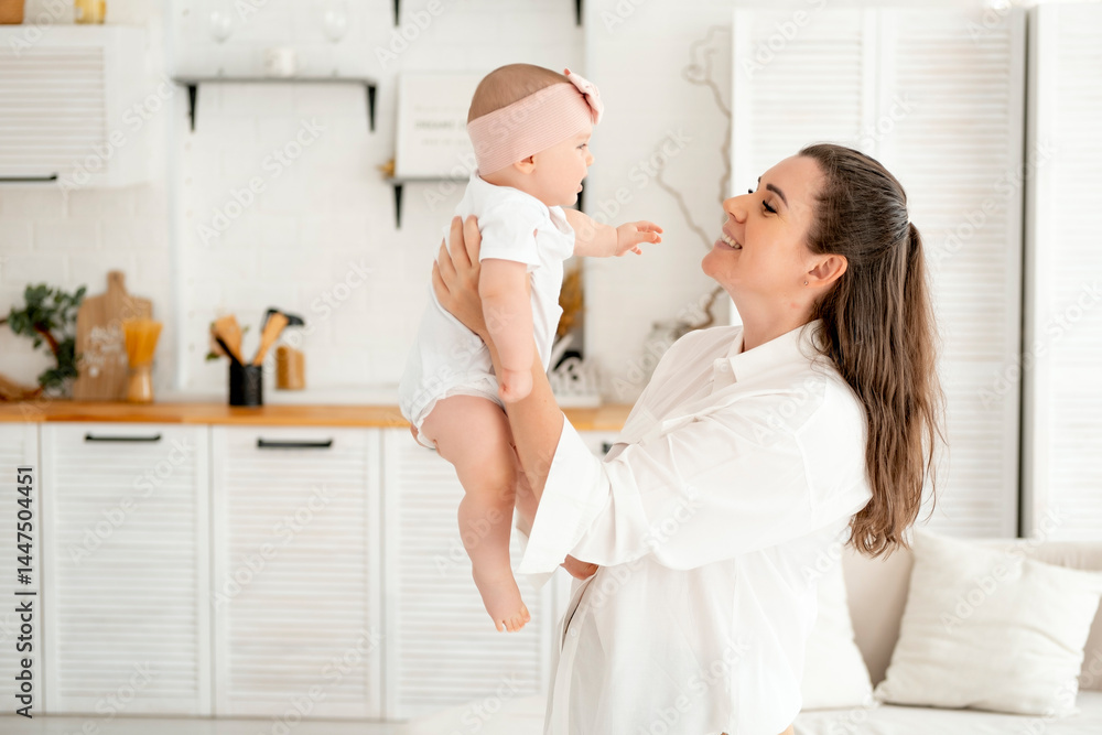 Fototapeta premium mom and baby hug and kiss at home in the bedroom, parental love and care, happy motherhood, mom with a baby in her arms, space for text