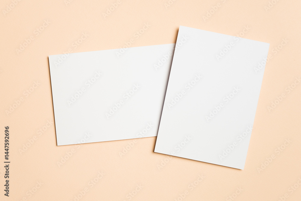 Two blank white cards arranged overlapping on a beige surface, one vertical and one horizontal, ideal for showcasing wedding invitations or elegant stationery. Two blank white cards arranged overlapping on a beige surface, one vertical and one horizontal, ideal for showcasing wedding invitations or elegant stationery.