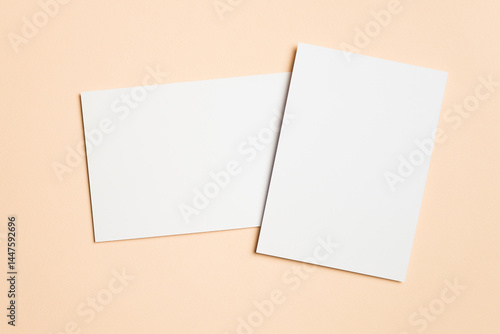 Two blank white cards arranged overlapping on a beige surface, one vertical and one horizontal, ideal for showcasing wedding invitations or elegant stationery.