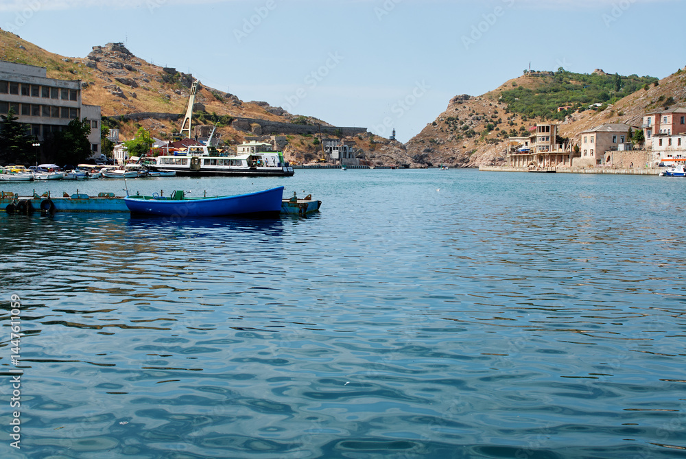 Fototapeta premium Serene Coastal Village with Blue Boat in Picturesque Harbor Setting..