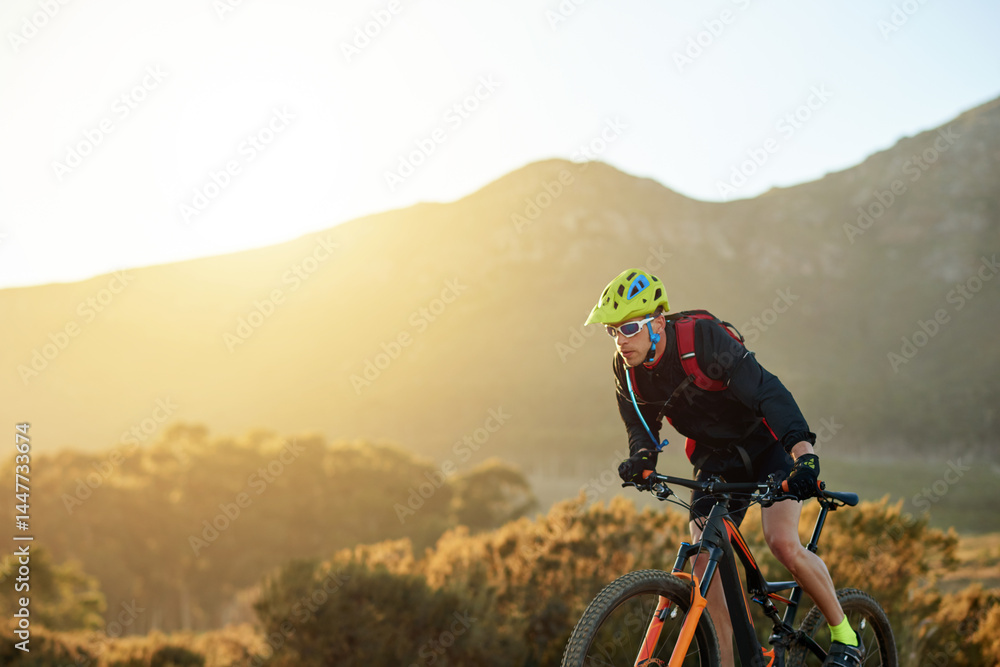 Naklejka premium Man, mountain or sunset with bike for cycling, extreme sport or fitness on dirt track in nature. Active, male person or cyclist riding with helmet on off road or desert terrain in outdoor wilderness