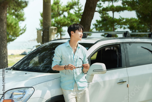Young Asian Man Leaning on White Car Outdoors