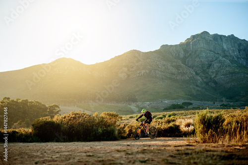 Bike, sports and view with man in mountains for adrenaline, adventure or training on dirt road. Exercise, fitness and scenic with person cycling in nature for challenge, competition or performance