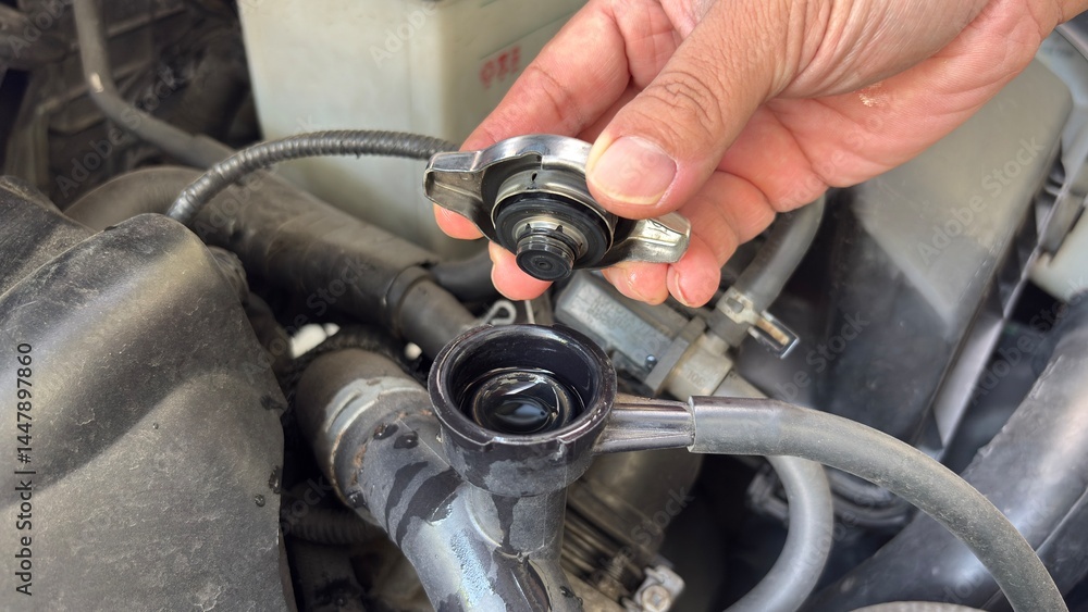 Hand of car auto mechanic engine, technician service check coolant cooling fluid water, he open radiator cap for change or repair the in garage. Check car radiator, car maintenance Hand of car auto mechanic engine, technician service check coolant cooling fluid water, he open radiator cap for change or repair the in garage. Check car radiator, car maintenance