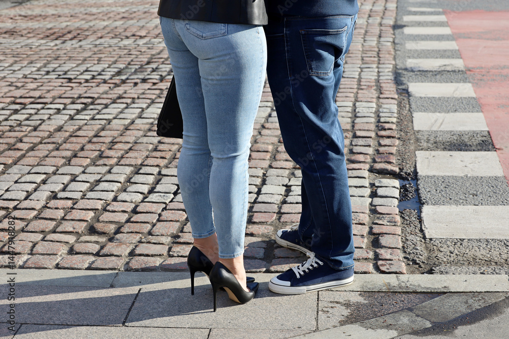 Couple in love on city street, male legs in sneakers and female in shoes on high heels. Romantic date, relationship