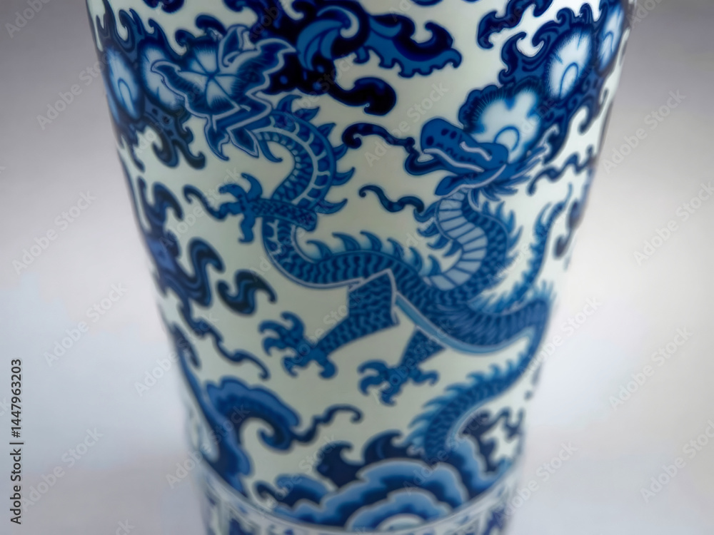 A blue and white vase with a dragon on it. The dragon is on the side of the vase and is surrounded by blue and white flowers