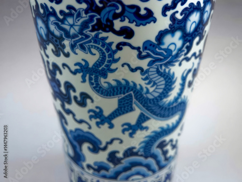 Obraz na płótnie A blue and white vase with a dragon on it. The dragon is on the side of the vase and is surrounded by blue and white flowers w salonie