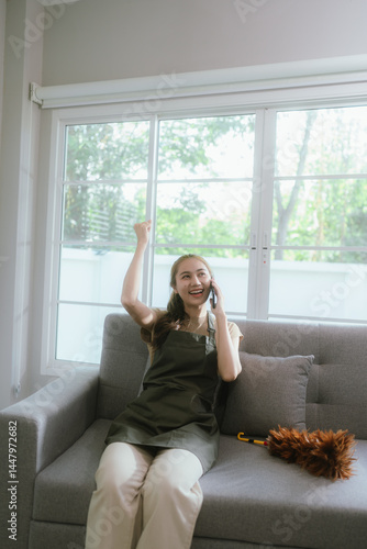 Free Download Smiling woman enjoying housework in a cozy, colorful living room, tidying up with satisfaction and care in a well-decorated space - GFXLoad