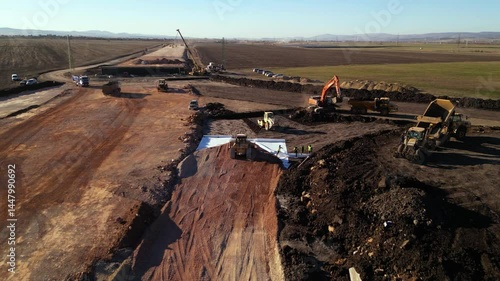 High angle top down late afternoon footage of bulldozer machine covering layers of geotextile with dirt and soil for the construction of a highway. Freeway build site with geosynthetic fabric burried
