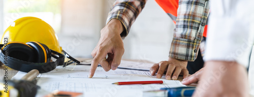 Close up hands of businessman from consultancy service discussing with project contractor and reviewing blueprint for build real estate facilities.