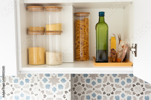 Organized kitchen pantry shelf with grains, olive oil bottle and pasta