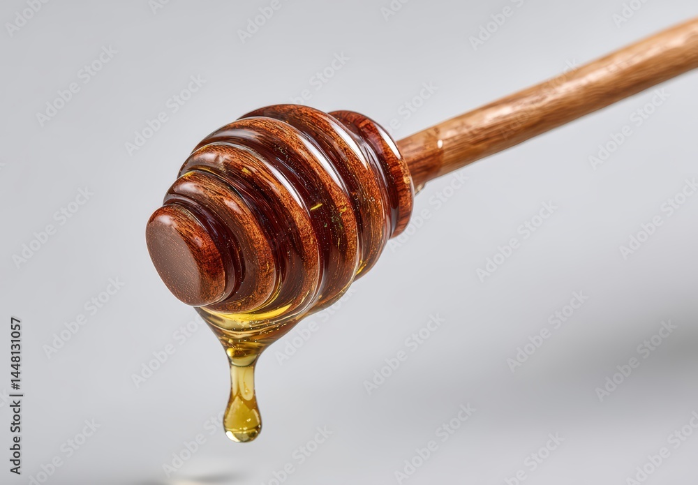 Wooden honey dipper with dripping golden honey on a grey background. Wooden honey dipper with dripping golden honey on a grey background.