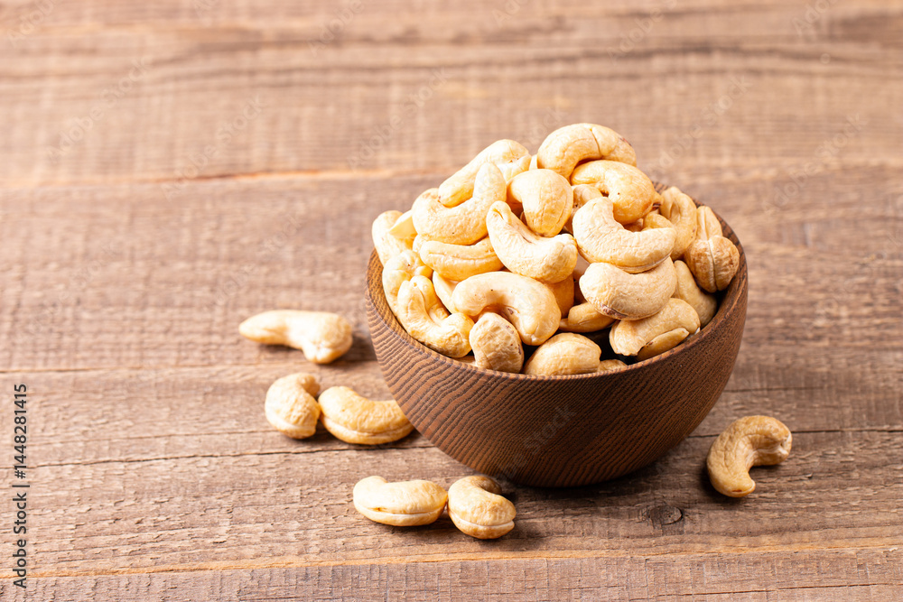 Organic roasted cashew nuts in a wooden bowl. Top view. Organic roasted cashew nuts in a wooden bowl. Top view.