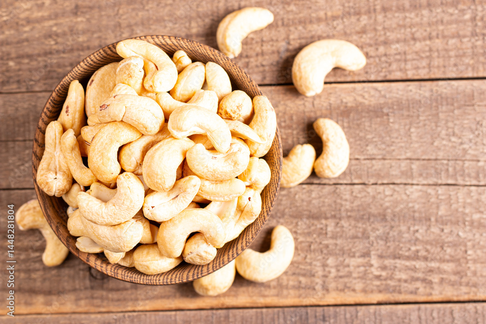 Fototapeta premium Organic roasted cashew nuts in a wooden bowl. Top view. 