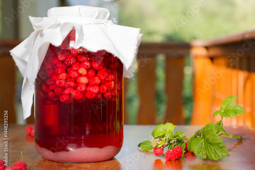 A jar full of raspberries under a white cover