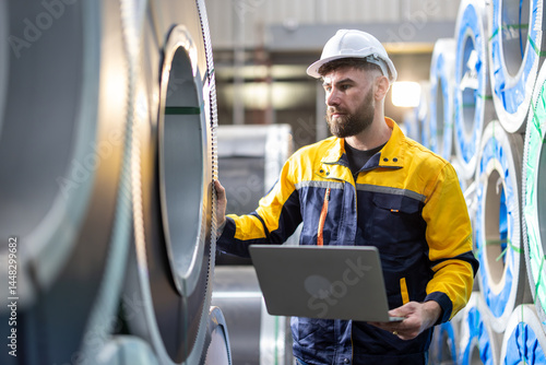 Technician industrial worker inspecting aluminum metal sheet fabricating roll check stock materials in the steel coil storage area, rolls metal sheet high quality durable meet standards industry.