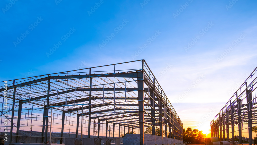 Fototapeta premium Silhouette of industry warehouse factory building framework with metal structure in construction site against sunset sky background, low angle view with copy space