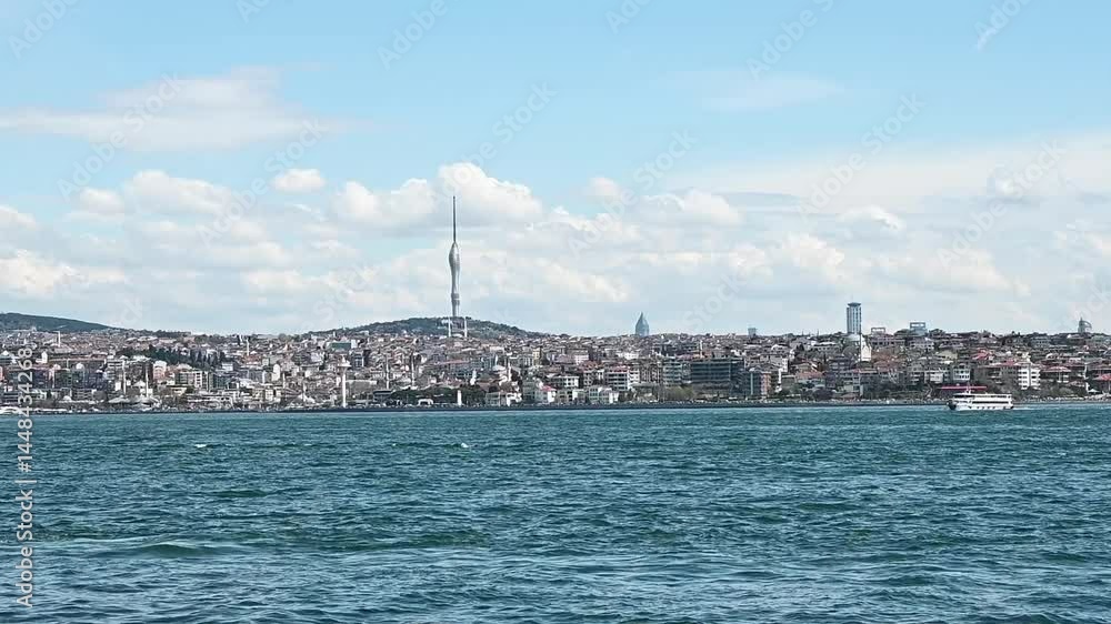 White ferry sails across Bosphorus with Istanbul skyline, TV tower and cloudy blue sky in background, capturing cityscape and water transport. Turkey. White ferry sails across Bosphorus with Istanbul skyline, TV tower and cloudy blue sky in background, capturing cityscape and water transport. Turkey.