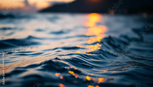 Rippling water surface reflecting sunset in dark blue, orange and yellow hues representing calm and serenity