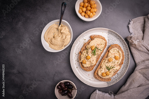 Obraz na płótnie Delicious sandwiches with hummus and ingredients on a dark background, top view, flat lay. High quality photo w salonie