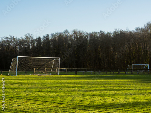 Obraz na płótnie A soccer field with a goal and a fence in the background. The sky is cloudy and the grass is green. Football training ground. Popular outdoor sport. Nobody. w salonie