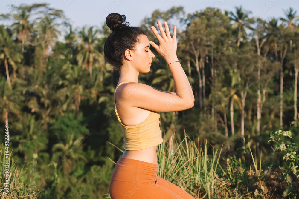 Young woman in Toe Squat asana near palm trees
