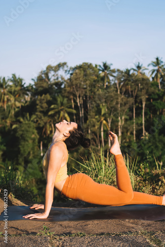 Obraz na płótnie Flexible woman doing stretching asana while practicing yoga in nature w salonie