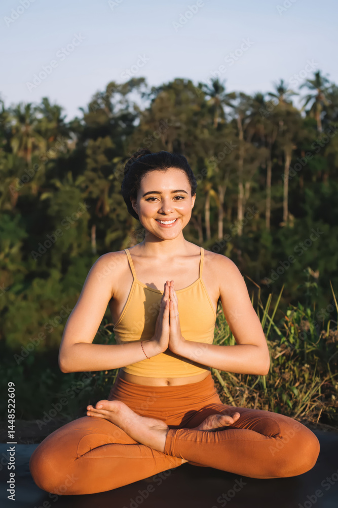 Smiling woman meditating on green grass