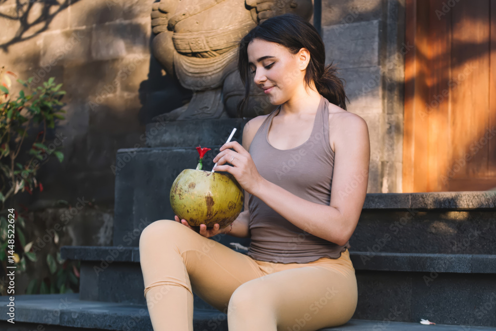Smiling woman with coconut drink on stairs