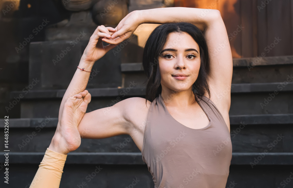 Young positive caucasian woman in tracksuit enjoying yoga practising reaching harmony and balance in retreat, 20s smiling female sitting in asana enjoying healthy physical and mental lifestyle