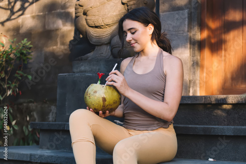 Obraz na płótnie Smiling woman with coconut drink on stairs w salonie