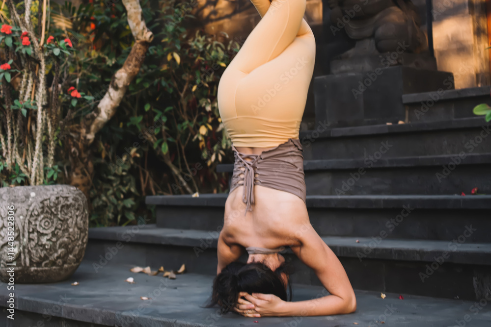 Young caucasian female standing on head in inverse pose during training reaching relaxation and harmony, back view of woman standing in asana practising in morning for keeping fit form