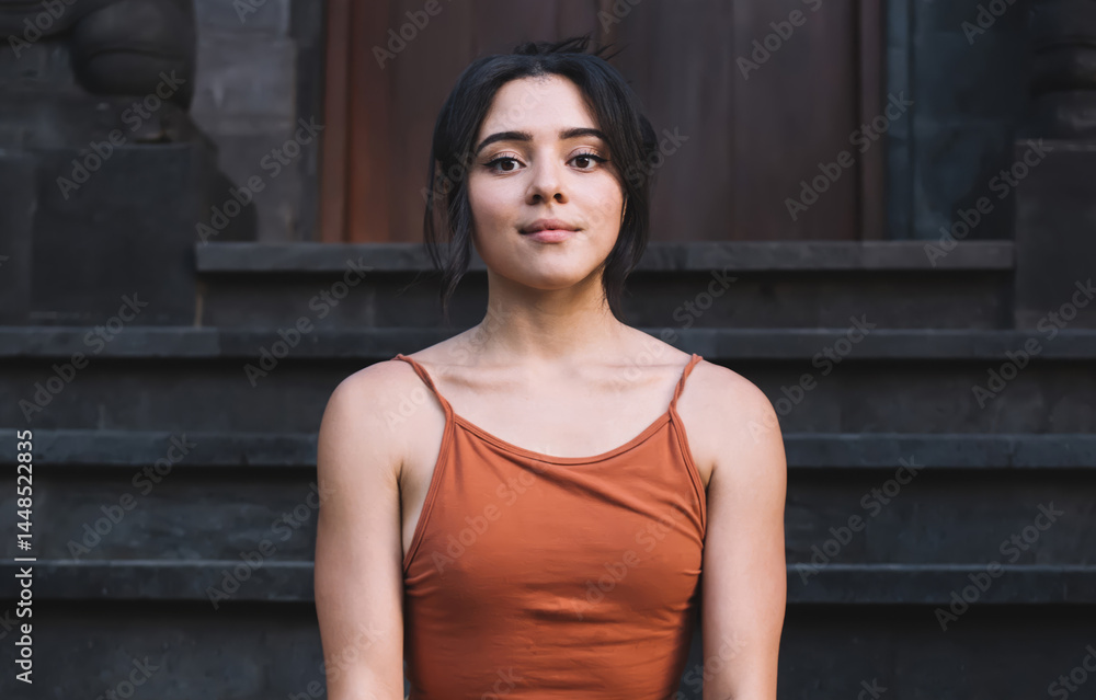 Young woman sitting in Butterfly Pose on stairs of temple